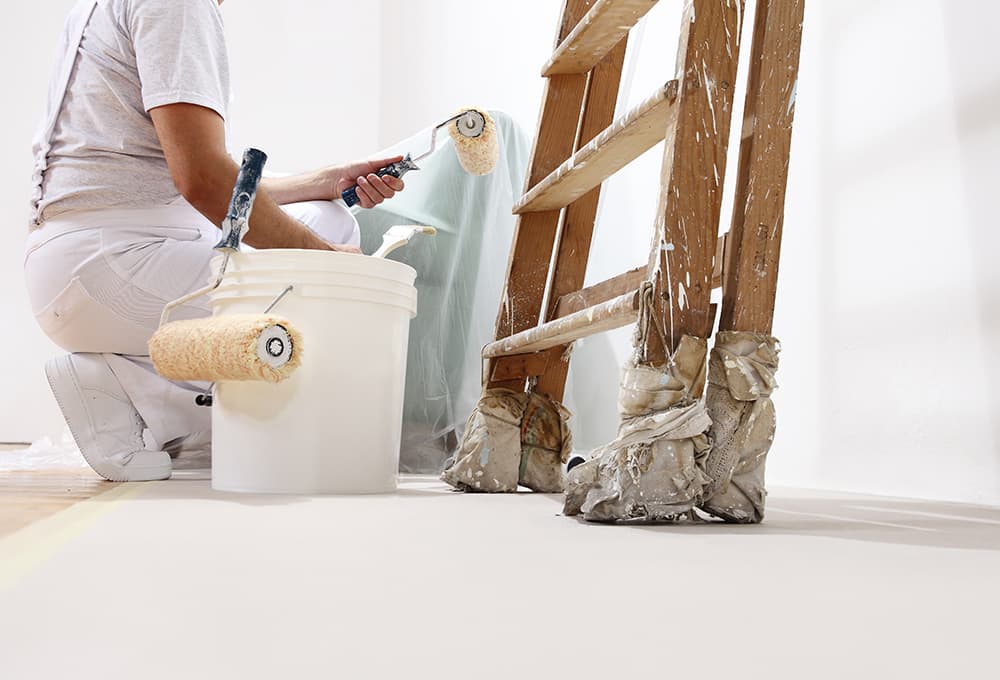 Painting Contractor with a pail of paint and paint rollers.